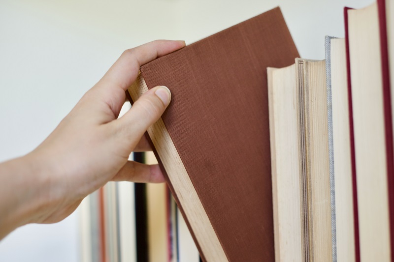 Someone selecting a book from shelf.